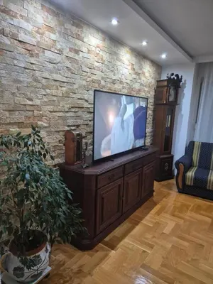 a living room with a flat screen tv on a brick wall at Apartment D in Krndija