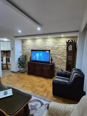 a living room with a flat screen tv on a brick wall at Apartment D&D in Krndija