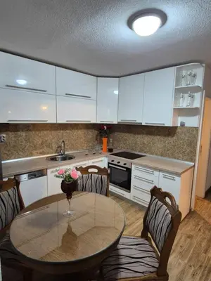 a kitchen with a table and chairs and white cabinets at Apartment D&D in Krndija