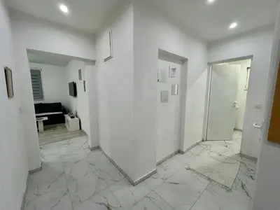 a hallway with white walls and a white door at Apartman M