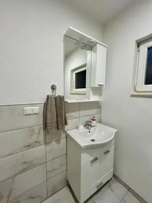 a white bathroom with a sink and a mirror at Apartman M