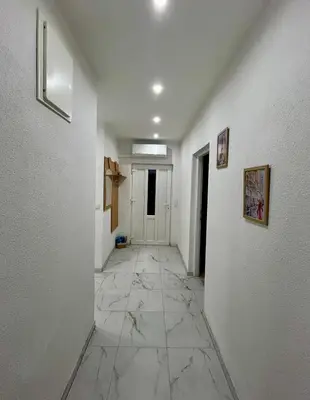 a hallway with white walls and a marble floor at Apartman M