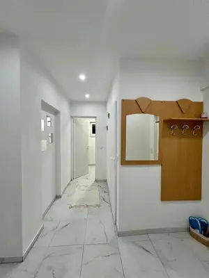 a hallway with white walls and a white tile floor at Apartman M
