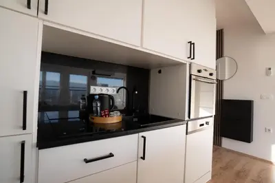 a kitchen with white cabinets and a black counter top at TheLuxPenthouseBugojno in Bugojno