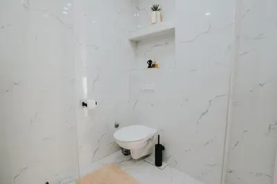 a white bathroom with a toilet and a glass shower at TheLuxPenthouseBugojno in Bugojno