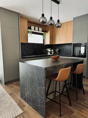 a kitchen with a black counter and two bar stools at Aurora Noir Retreat in Banja Luka