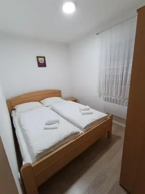 a bedroom with a bed with white sheets and a window at Divan Vlašić in Šišava