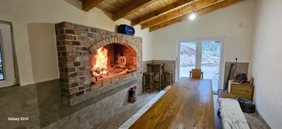 a living room with a brick fireplace with a fire at Divan Vlašić in Šišava