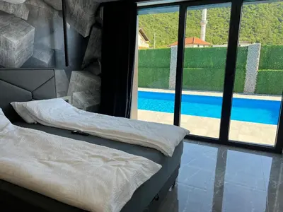 a bedroom with a view of a swimming pool through a window at villa M&B in Zbilje