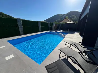 a blue swimming pool with two chairs and a fence at villa M&B in Zbilje