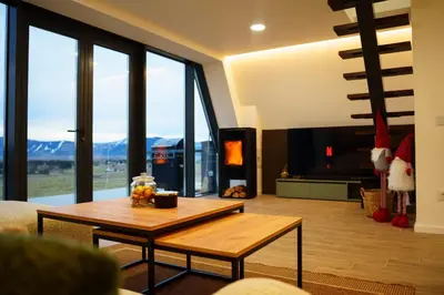 a living room with a table and large windows at The Sky Hill - luxury chalet in Kupres