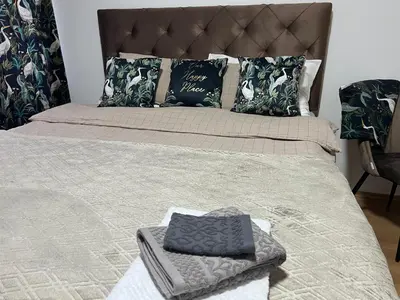 a bed with a gray blanket and pillows on it at Chill In Apartman in Banja Luka