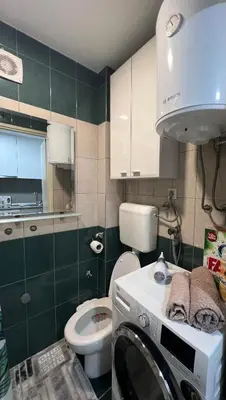 a bathroom with a toilet and a washing machine in it at Chill In Apartman in Banja Luka