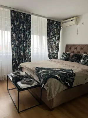 a bedroom with a large bed and a table at Chill In Apartman in Banja Luka