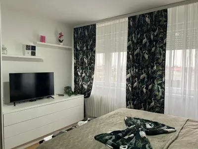 a bedroom with a flat screen tv and a bed at Chill In Apartman in Banja Luka