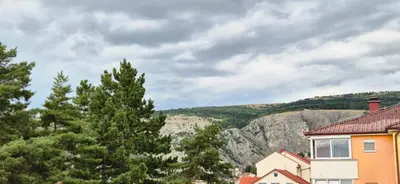 a house and trees with a mountain in the background at Livno Sympan in Livno