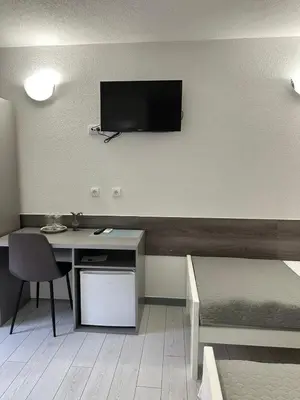 a room with a bed and a desk and a tv on the wall at Banja Luka Arcadia in Banja Luka