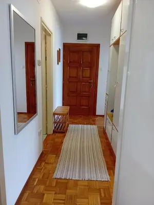 a hallway with a door and a rug and a mirror at Apartman BRKO in Bihać
