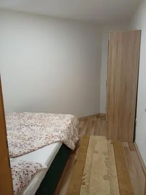 a bedroom with a bed and a wooden door at Apartman Školska in Travnik