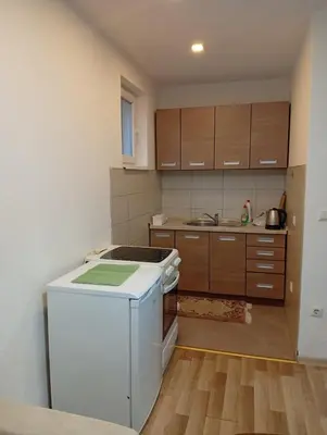 a kitchen with a white refrigerator and wooden cabinets at Apartman Školska in Travnik