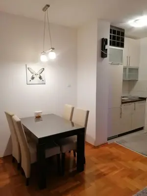 a dining room with a table and chairs and a kitchen at Apartman 44, Mejdan, Banja Luka in Banja Luka