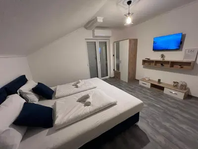 a bedroom with a large bed and a flat screen tv at DM Rooms l in Gornji Vakuf