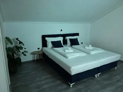 a bedroom with a large bed with white sheets and a table at DM Rooms l in Gornji Vakuf