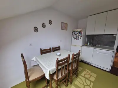a kitchen with a table and some chairs and a refrigerator at Apartman Sofija 3 in Starčevica