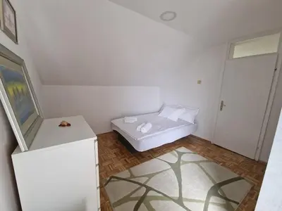 a small white room with a bed and a door at Apartman Sofija 3 in Starčevica