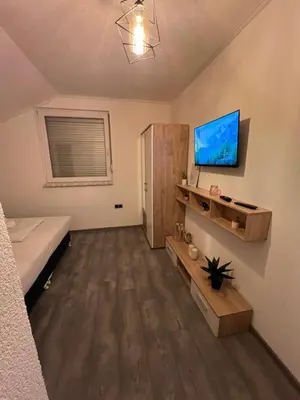 a bedroom with a bed and a tv on a wall at DM Rooms lll in Gornji Vakuf