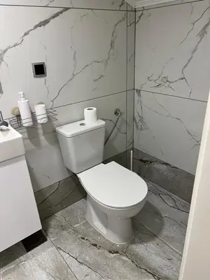 a white toilet in a bathroom with marble walls at DM Rooms lll in Gornji Vakuf