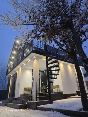 a white house with a staircase in the snow at Villa Perla in Prijedor