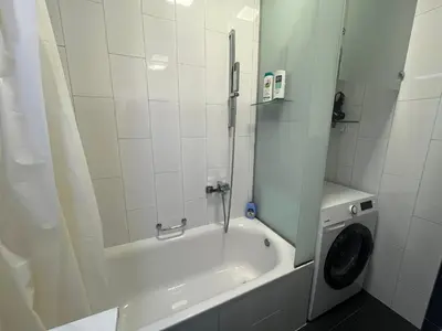 a bathroom with a tub and a washing machine at Apartman Dona in Banja Luka