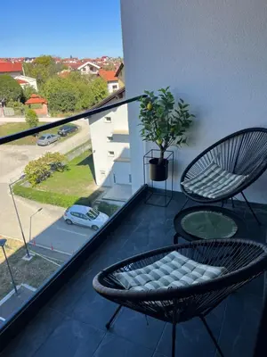 a balcony with a chair and a table and a window at Gold Panorama Apartment 27 in Banja Luka