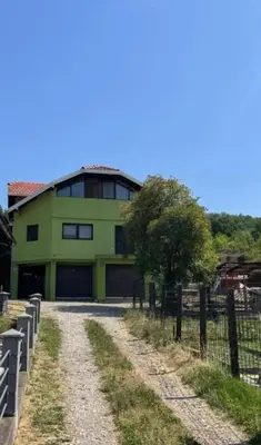 a green building with a fence next to a dirt road at Panonska jezera ZELENA OAZA in Tuzla