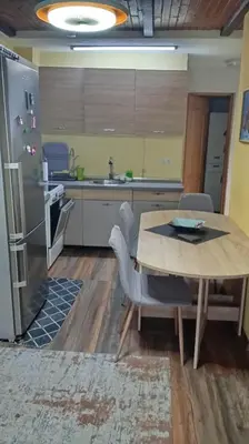 a kitchen with a wooden table and a refrigerator at Panonska jezera ZELENA OAZA in Tuzla