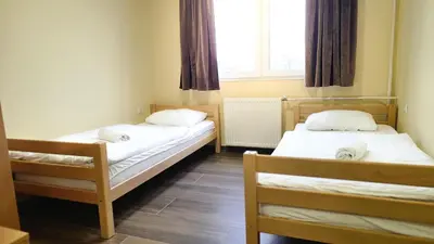 two beds in a small room with a window at City Hostel Banja Luka in Banja Luka