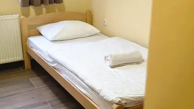 a bed in a small room with white sheets and a pillow at City Hostel Banja Luka in Banja Luka