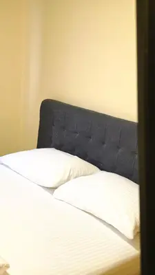 a bed with a blue headboard and two pillows at City Hostel Banja Luka in Banja Luka