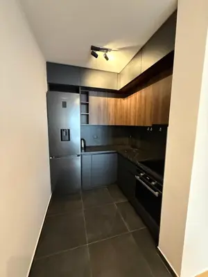 a kitchen with black cabinets and a refrigerator at Apartman sa dvije sobe in Banja Luka