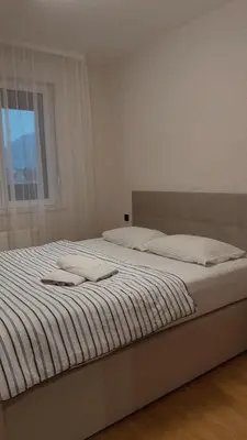 a bedroom with a bed with white sheets and a window at Apartman sa dvije sobe in Banja Luka