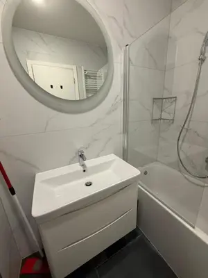 a white bathroom with a sink and a mirror at Apartman sa dvije sobe in Banja Luka
