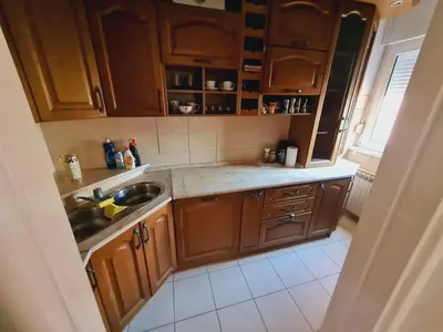 a small kitchen with wooden cabinets and a sink at KT Apartment City Centar in Banja Luka