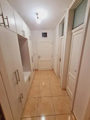 a hallway with white cabinets and a tiled floor at KT Apartment City Centar in Banja Luka