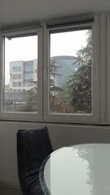 a table and a chair in a room with two windows at Stan na dan in Visoko
