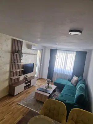 a living room with a blue couch and a tv at Apartman Green Oaza in Doboj
