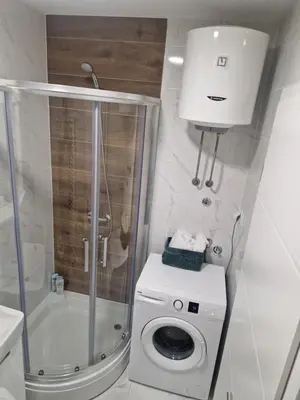 a bathroom with a washing machine and a shower at Apartman Green Oaza in Doboj