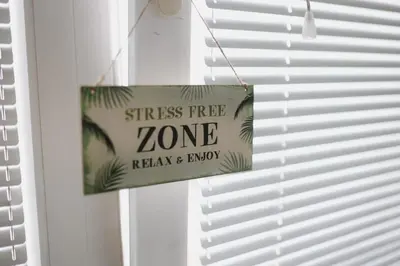 a sign that reads stress free zone relax and enjoy hanging from a window at Apartman CENTRAL LOFT Gradiška in Bosanska Gradiška