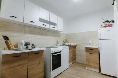 a kitchen with white appliances and wooden cabinets at Apartman CENTRAL LOFT Gradiška in Bosanska Gradiška