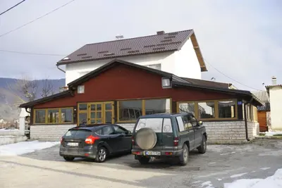 two cars parked in front of a building at Apartman Anita in Kupres